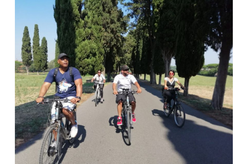 Gruppe von Menschen auf dem Fahrrad zwischen Zypressen